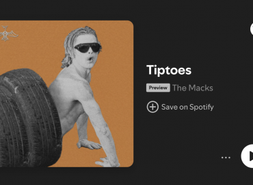 Picture of man painted white with sunglasses climbing out of a tire tunnel to promote The Macks new song "Tiptoes"